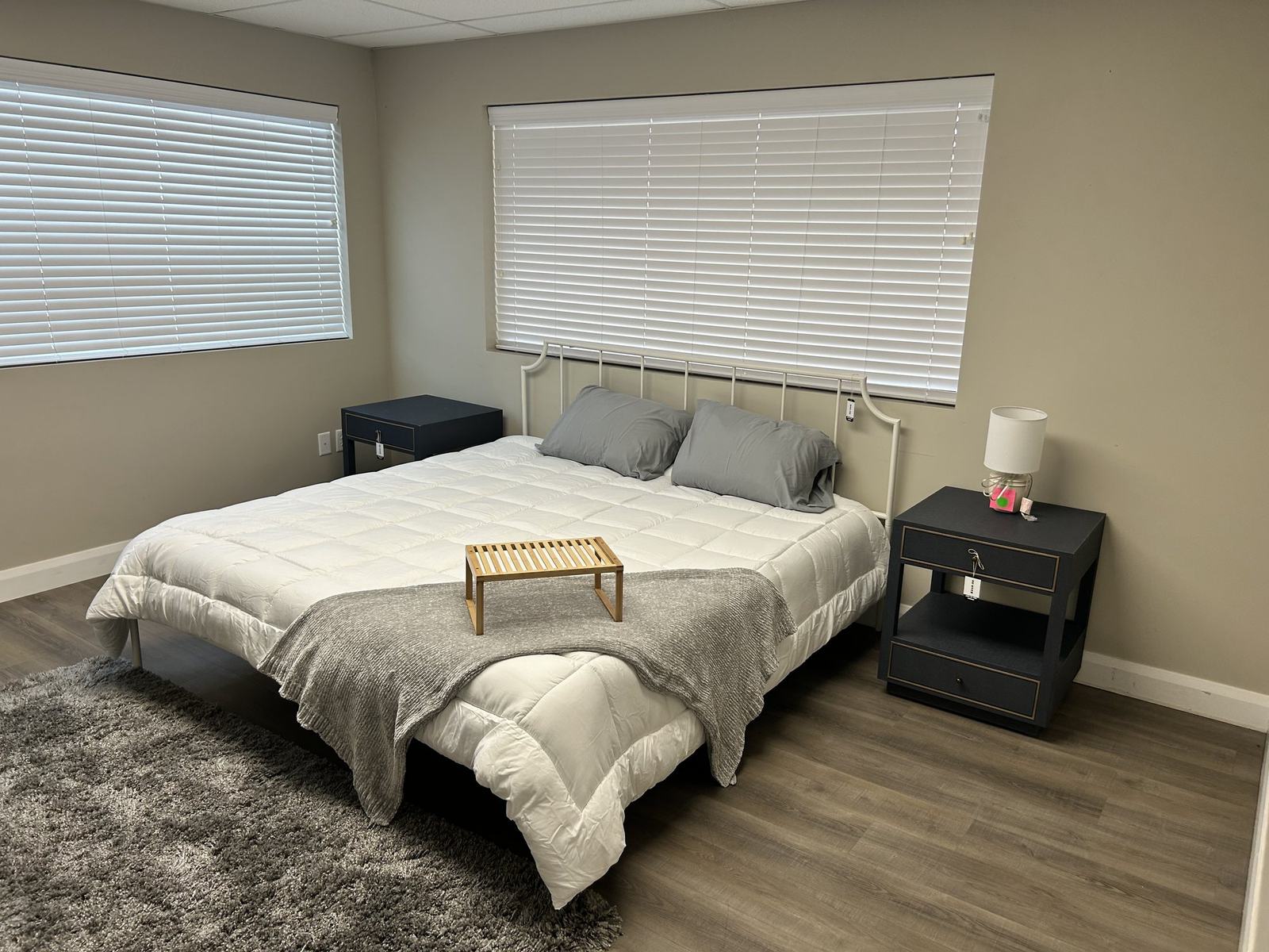 A made bedroom set on display with nightstands, table lamp and a wooden breakfast tray