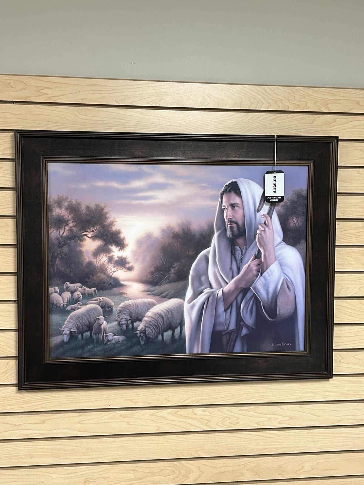A large framed painting displayed on slatwall in the consignment showroom