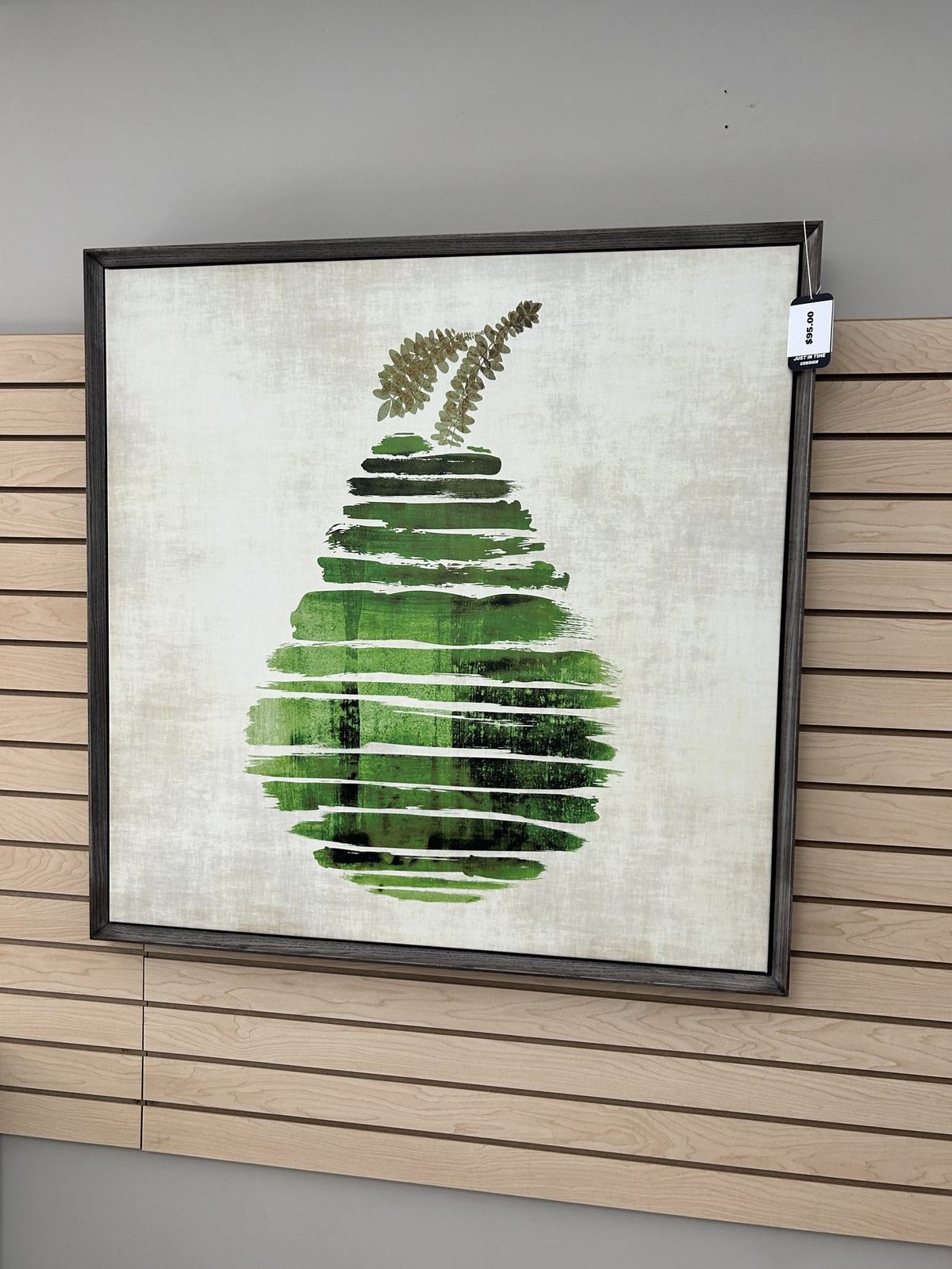 A large framed artwork of a green pear on a textured cream background