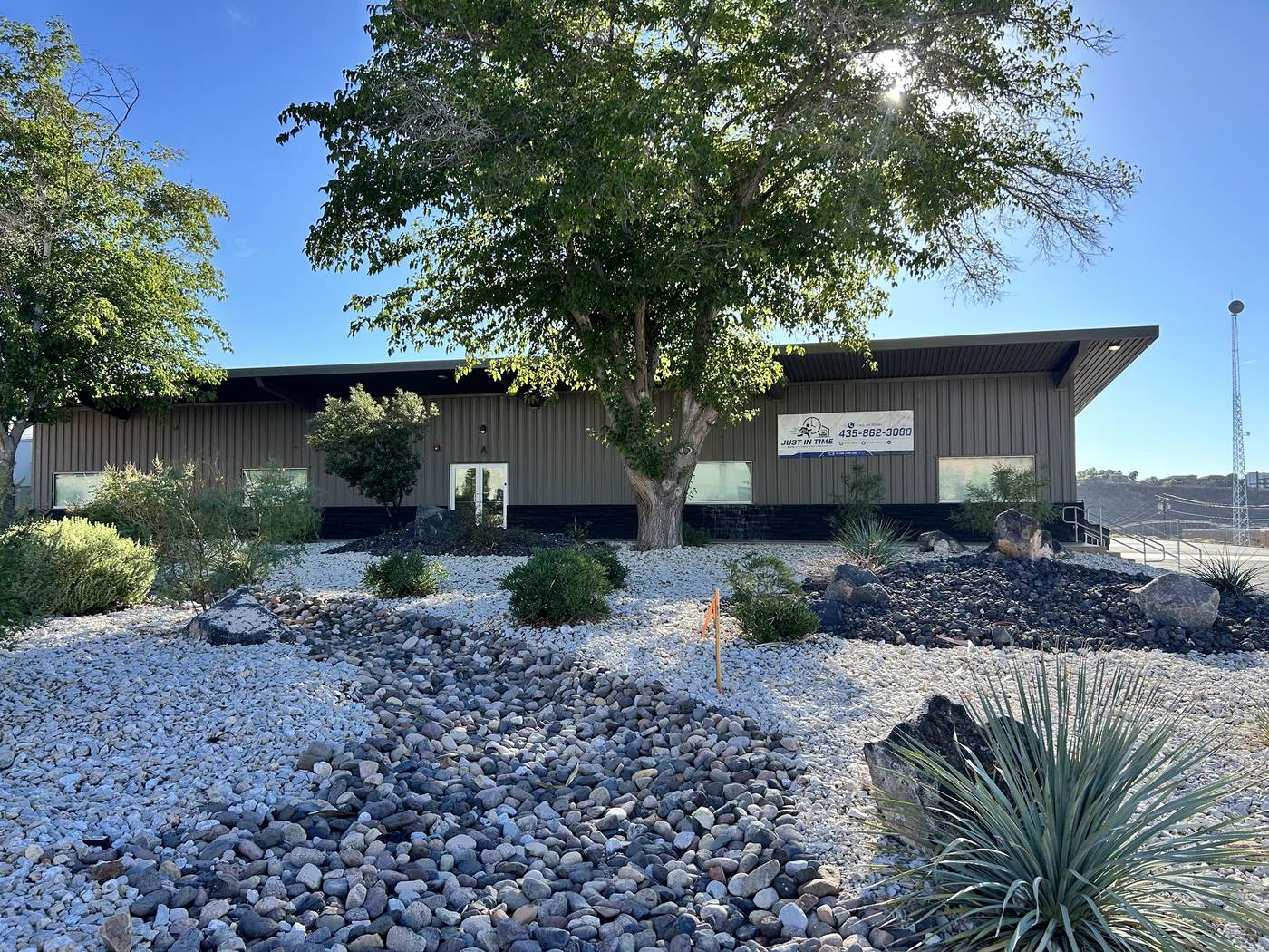 The Just-In Time Consignment showroom building in St. George, Utah, with desert landscaping and a shade tree out front