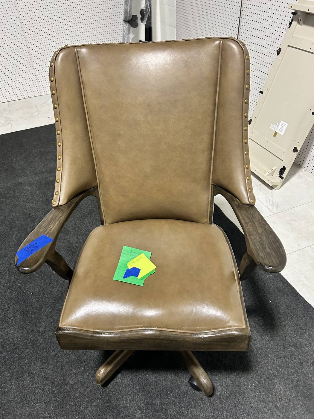 A tan leather executive office chair on casters, tagged for consignment